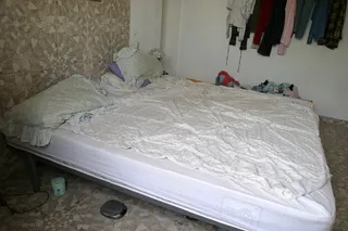 A bare mattress on a bed in a small room, a photograph from the exhibition