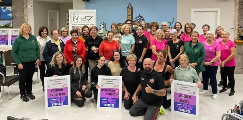 Mujeres con carteles de campaña de la EUW Marina Alta en un encuentro comunitario en Benitachell