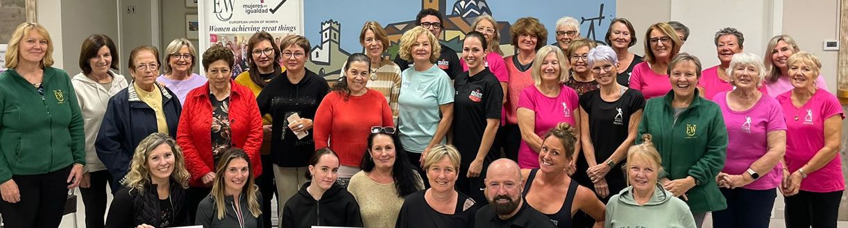 Un grupo numeroso de la comunidad ante la pancarta de la EUW y Mujeres en Igualdad