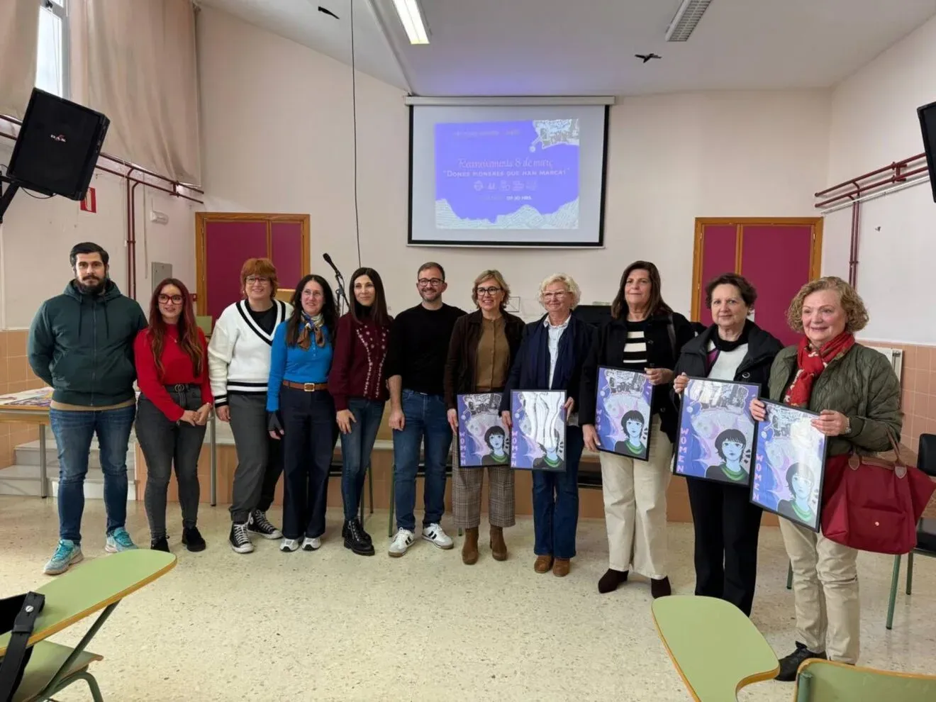 Women and men at IES Antoni Llidó holding framed portraits of pioneering women