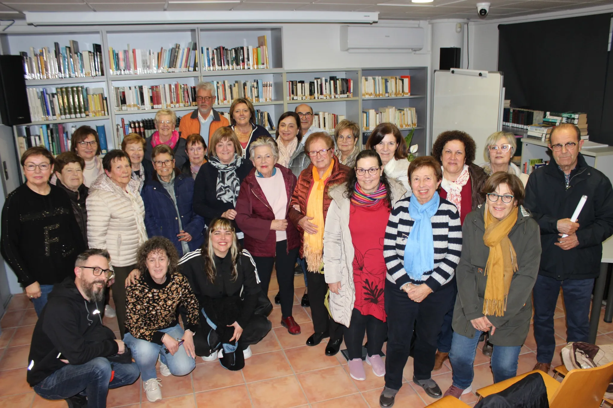Women and a few men gathered in a library in Benitachell